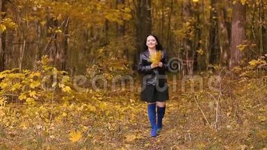 一位穿着蓝色靴子的年轻黑发女子正走在一个秋天的公园里，手里拿着黄叶